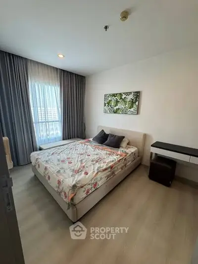 Cozy bedroom with modern decor and large window offering natural light.