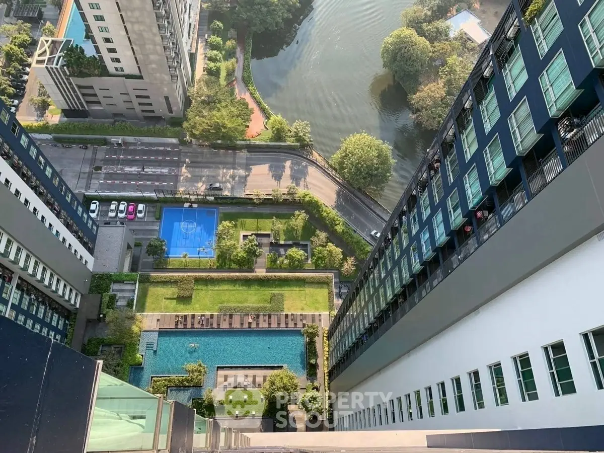 Stunning aerial view of modern high-rise building with pool and garden, offering urban luxury and scenic surroundings.