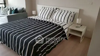 Modern bedroom with stylish striped bedding and cozy seating area