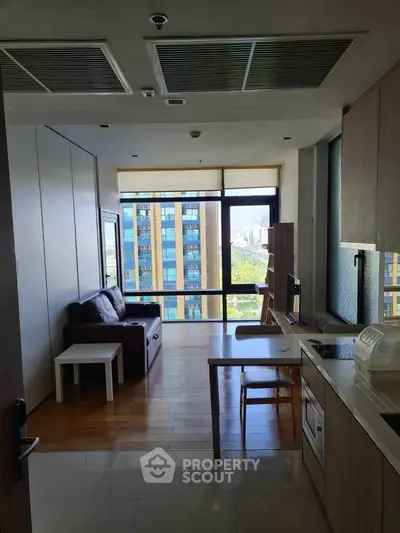 Modern apartment with open kitchen and city view, featuring sleek furnishings and large windows.