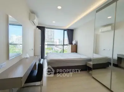 Modern bedroom with city view, featuring sleek furniture and large mirrored wardrobe.