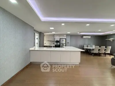 Spacious modern kitchen with open layout and dining area, featuring sleek design and ample lighting.