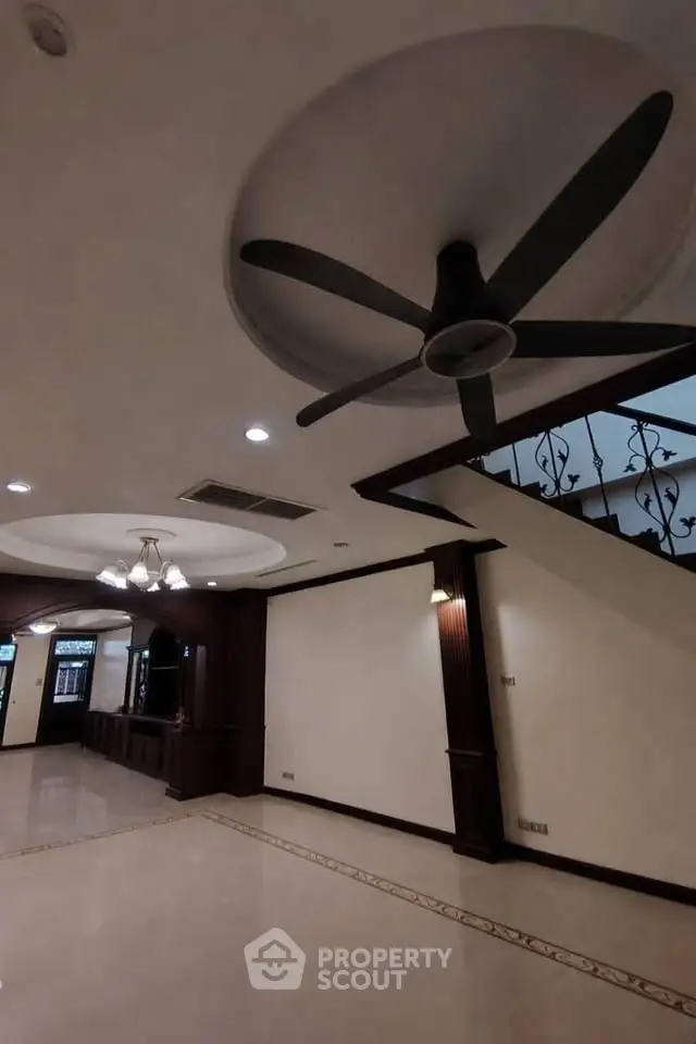 Spacious interior with elegant ceiling fan and staircase, perfect for modern living.