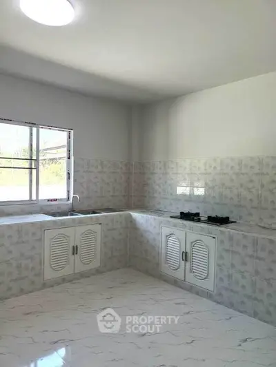 Spacious kitchen with modern gas stove and ample natural light, perfect for culinary enthusiasts.