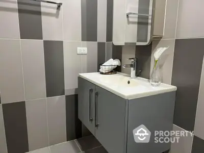 Sleek modern bathroom with stylish gray and white tiles, featuring a contemporary vanity unit with ample storage space.