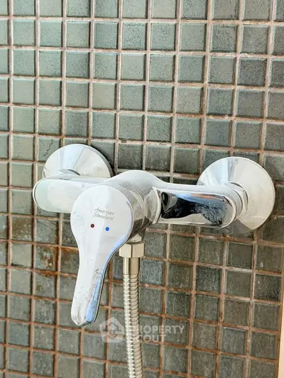 Modern bathroom shower fixture with sleek chrome finish and tiled wall.
