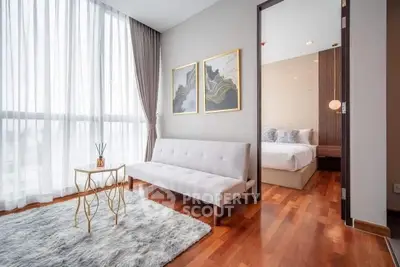 Stylish modern living room with elegant decor and natural light, adjacent to a cozy bedroom.