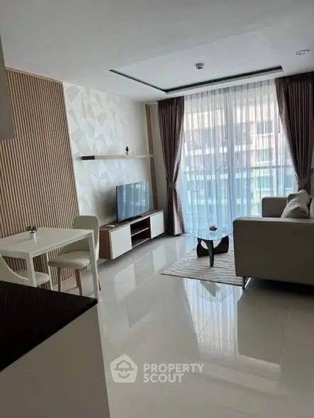 Modern living room with sleek furniture and large window offering natural light.