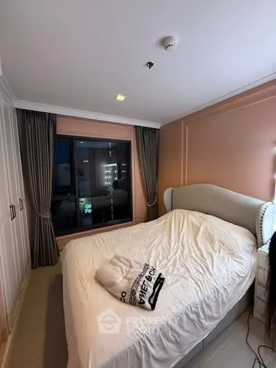 Cozy bedroom with elegant design and large window offering city views, perfect for relaxation and comfort.