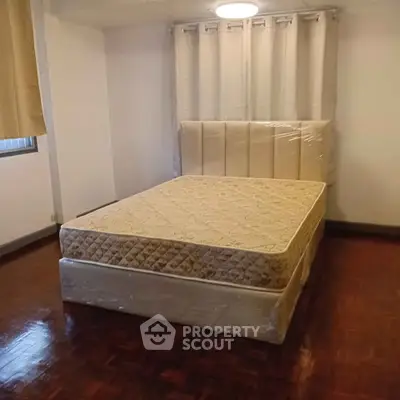 Spacious bedroom with a comfortable bed and elegant wooden flooring, perfect for relaxation.