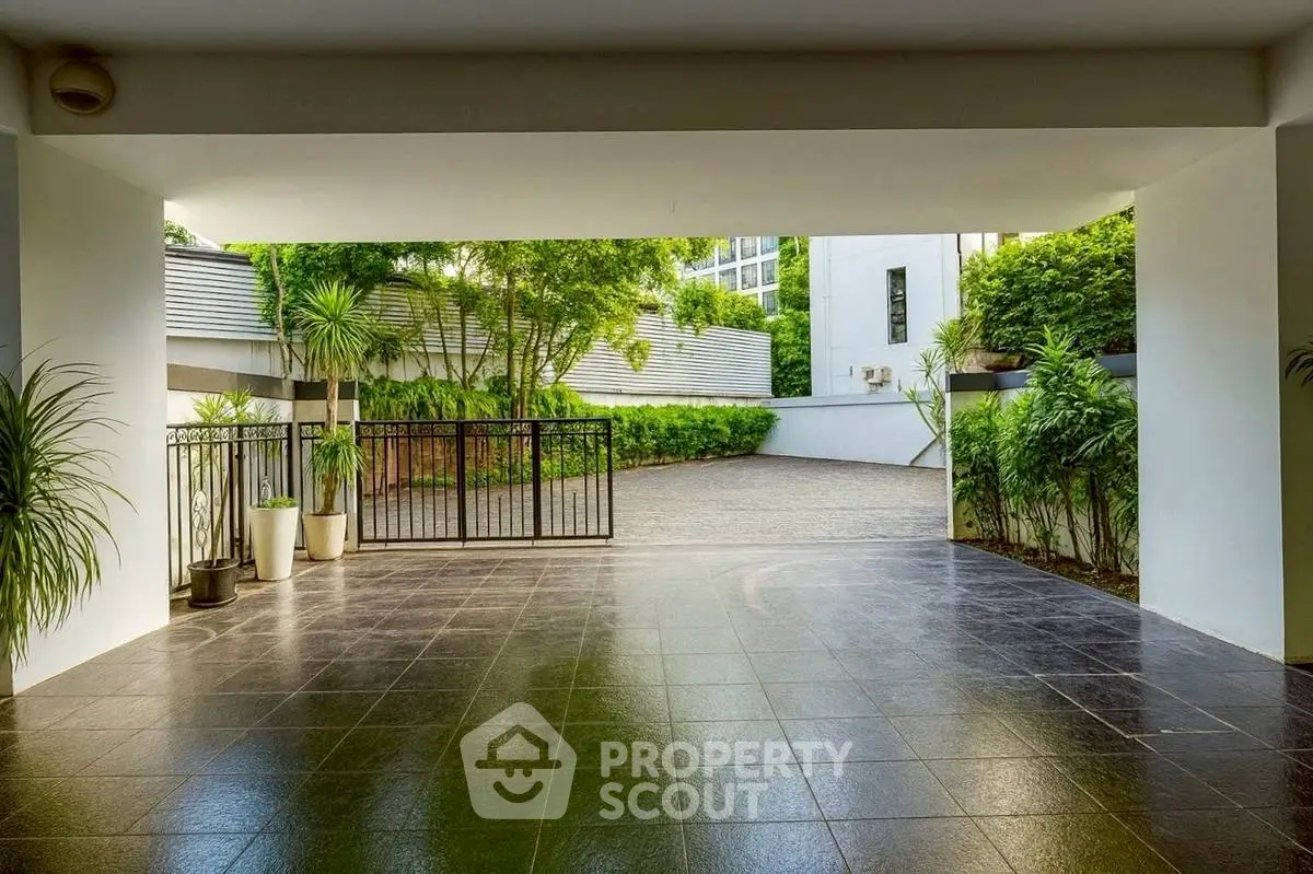 Spacious modern entrance with sleek tiles and lush greenery, perfect for welcoming guests.