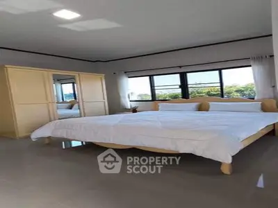 Spacious bedroom with large windows and elegant furnishings in a modern home.
