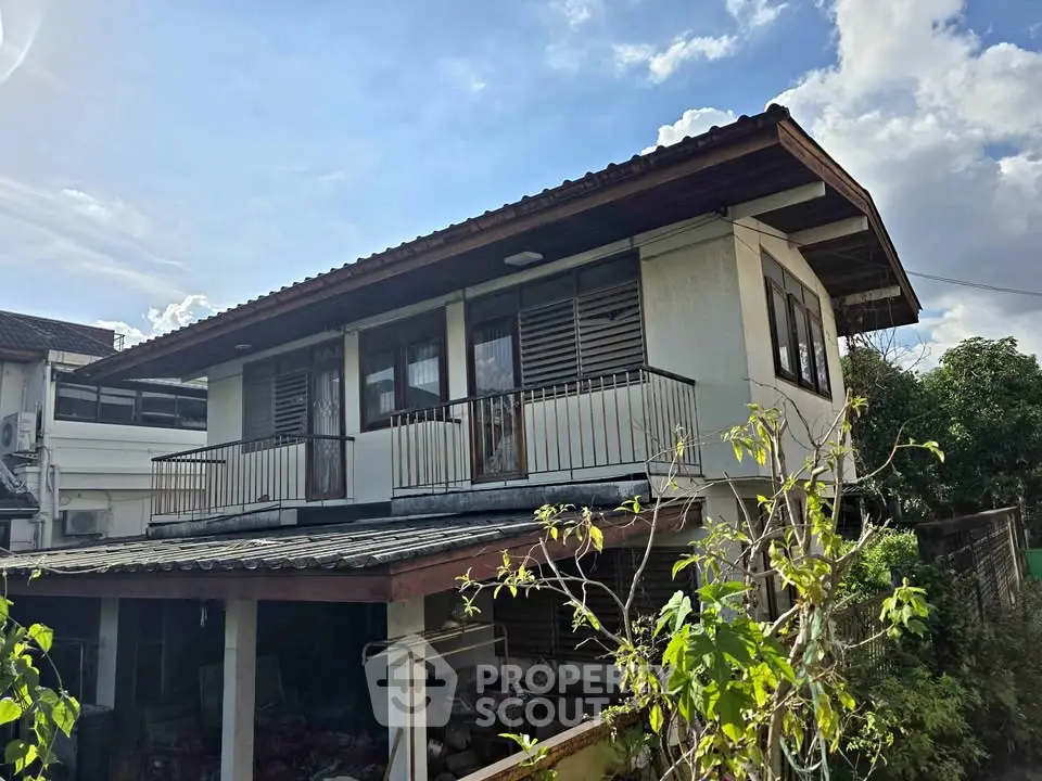 Charming two-story house with balcony and lush greenery