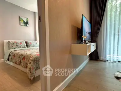 Modern bedroom with floral bedding and wall-mounted TV, featuring elegant floor-to-ceiling curtains.