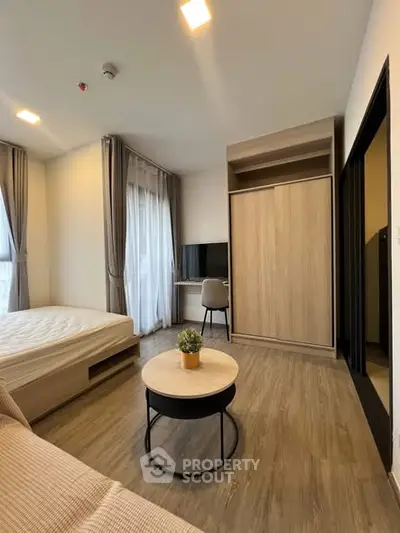 Modern bedroom with cozy decor and natural light, featuring a stylish wardrobe and compact workspace.