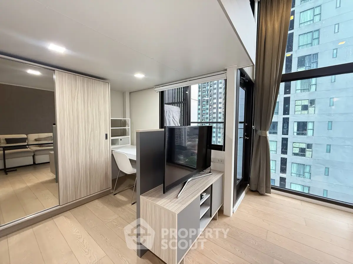 Modern living room with sleek furniture and large windows in a high-rise apartment.