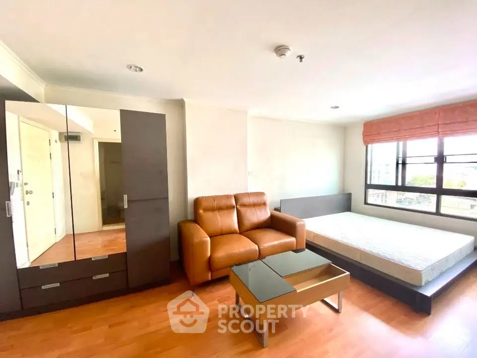 Spacious studio apartment with modern furnishings and large windows for natural light.