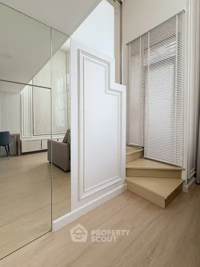 Modern interior with elegant staircase and mirrored wall in stylish living space.
