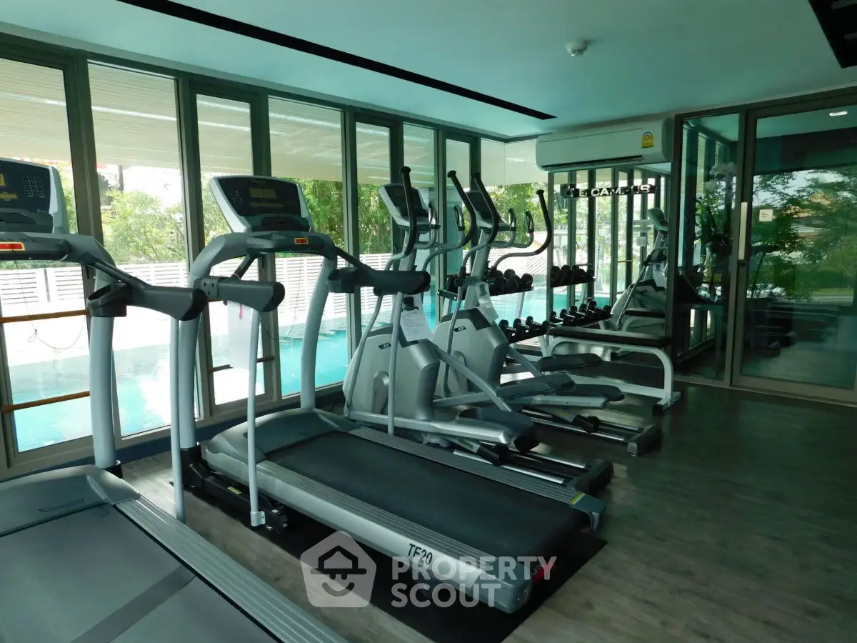 Modern gym with treadmills and pool view in luxury real estate property.