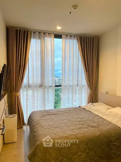 Spacious bedroom with large window offering stunning city views, perfect for relaxation and comfort.