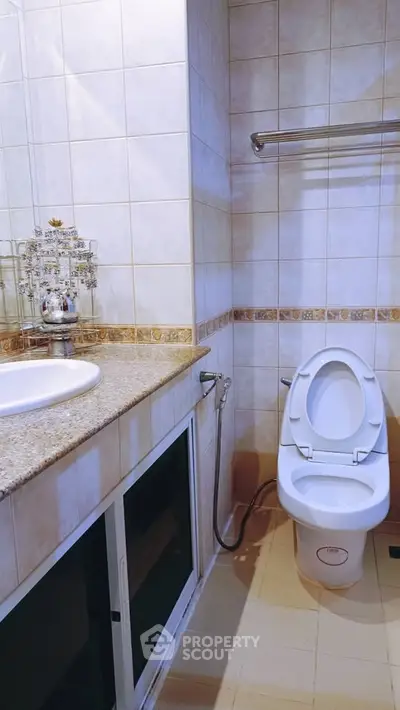 Modern bathroom with elegant fixtures and tiled walls, featuring a sleek countertop and toilet.
