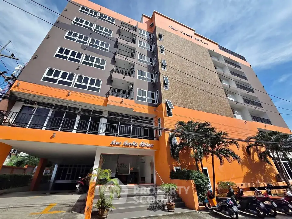 Modern apartment building with vibrant orange facade and palm trees, offering urban living in a prime location.