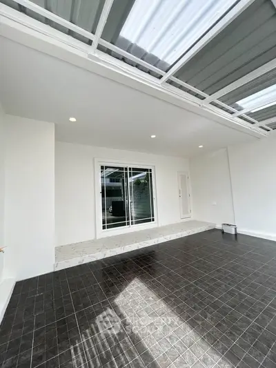 Spacious modern patio with sleek tiled flooring and sliding glass doors, perfect for outdoor relaxation.