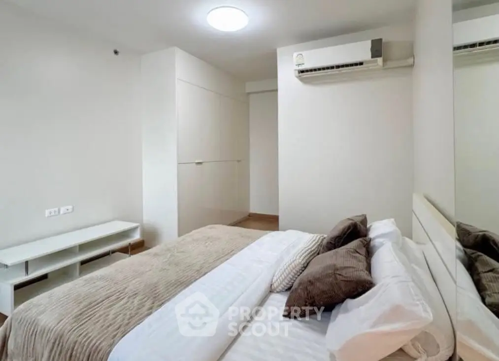 Modern bedroom with neutral tones and air conditioning in a stylish apartment.