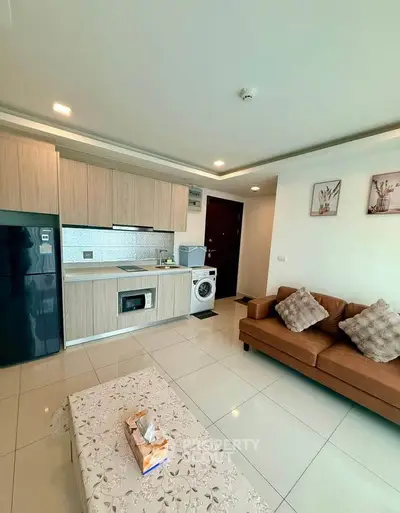 Modern open-layout living room with kitchen, featuring sleek appliances and cozy seating area.
