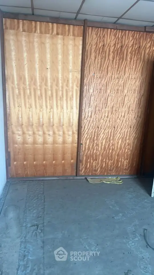 Spacious room with wooden sliding doors and unfinished flooring, ideal for customization.