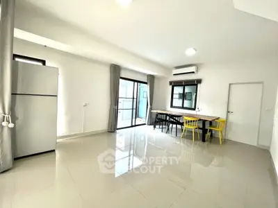 Spacious modern living area with large windows and dining space, featuring sleek tile flooring and bright natural light.
