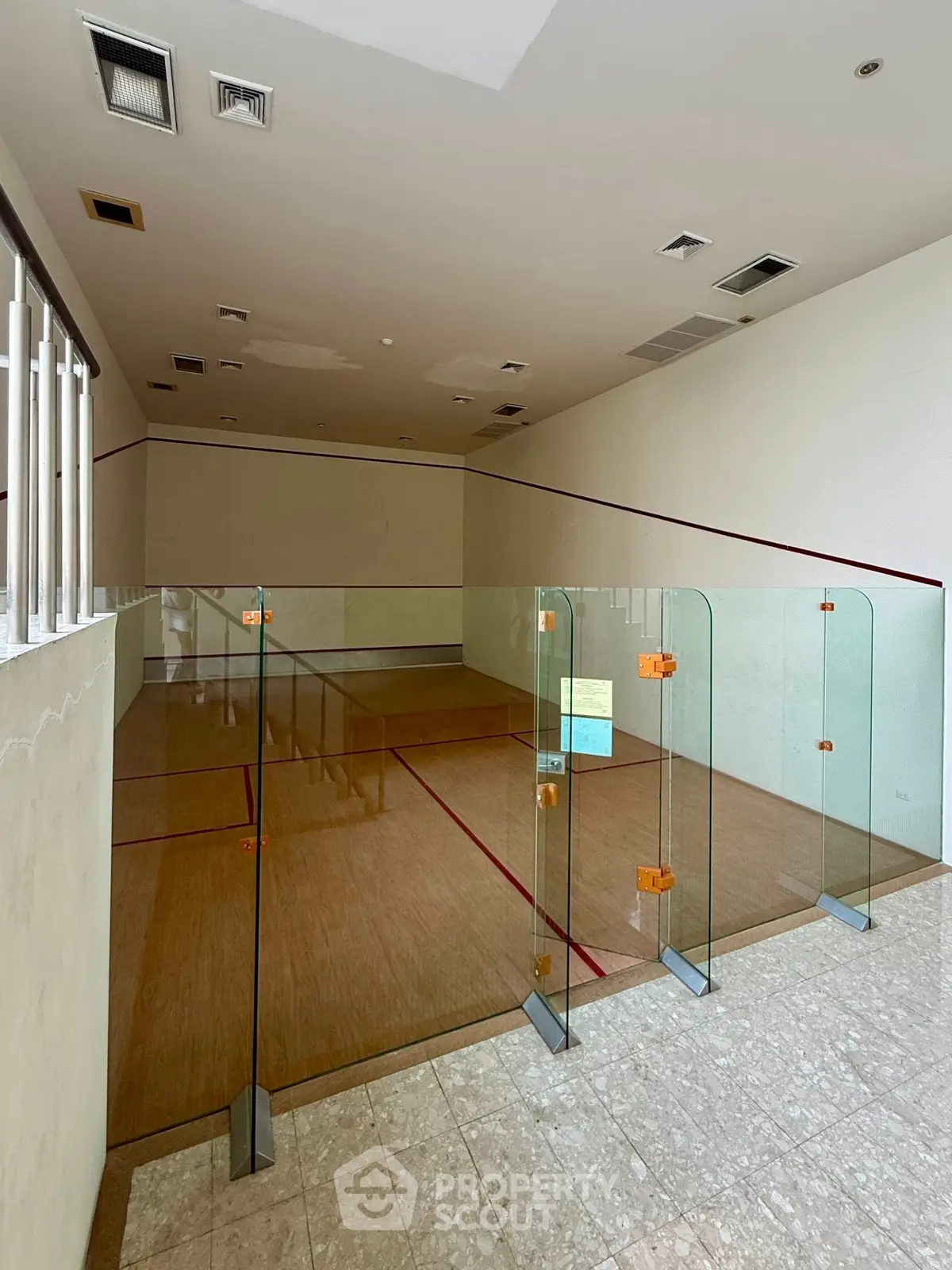 Spacious indoor squash court with glass walls in modern residential building.