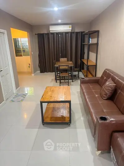 Modern living room with leather sofa and wooden furniture, featuring a cozy dining area.