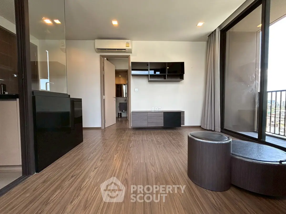 Modern living room with wooden flooring and balcony view in a stylish apartment.