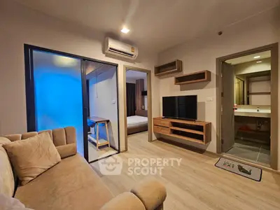 Modern living room with cozy sofa, TV, and air conditioning, leading to a stylish bedroom and bathroom.