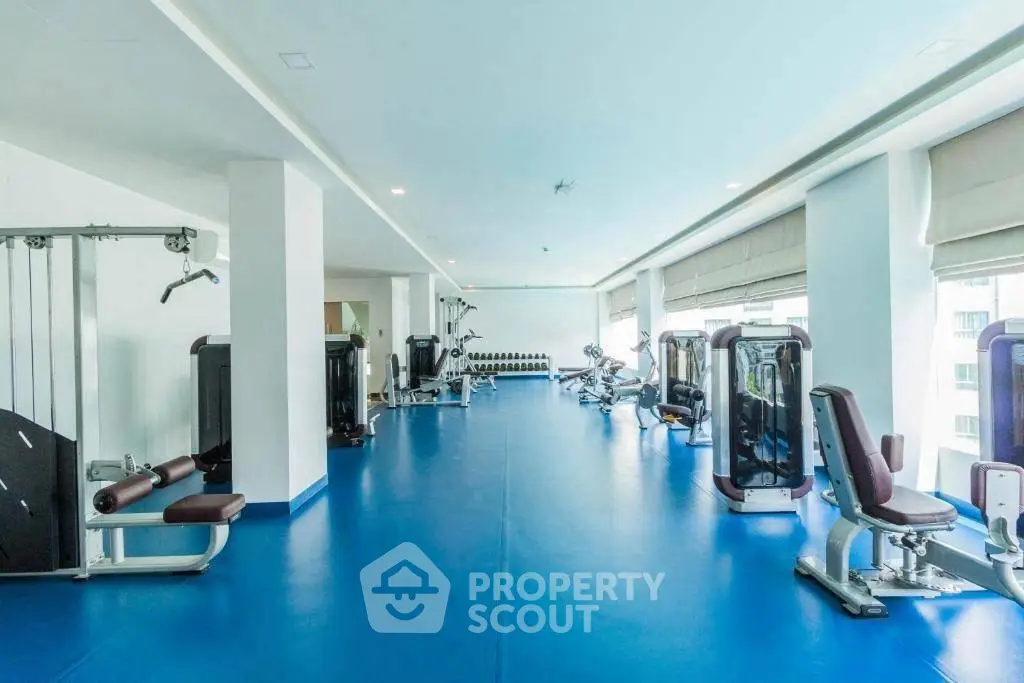 Spacious gym with modern equipment and large windows in a luxury residential building.