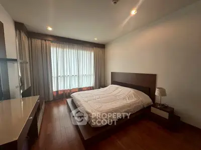 Spacious bedroom with modern wooden flooring and large window for natural light.