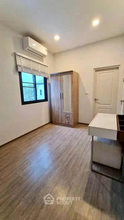 Modern bedroom with wooden flooring, air conditioning, and sleek wardrobe design.