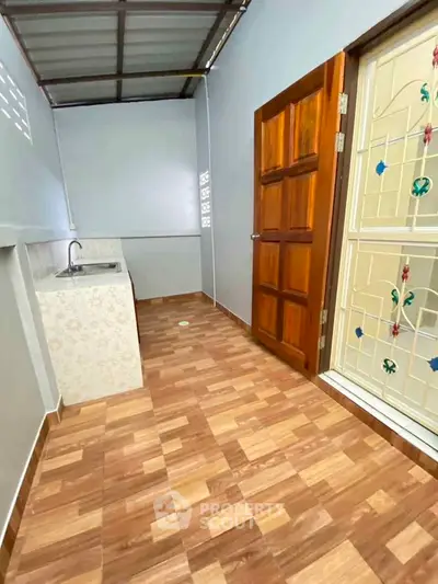 Charming utility area with wooden door and decorative glass, featuring a compact sink and tiled flooring.