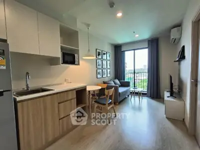 Modern living room with open kitchen, cozy seating, and large window with city view.