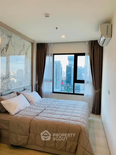 Modern bedroom with city view, featuring elegant decor and large window for natural light.