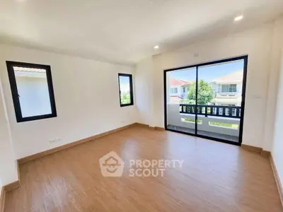 Spacious bright room with wooden flooring and large windows offering scenic views.