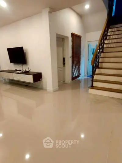 Spacious modern living room with sleek TV setup and elegant staircase