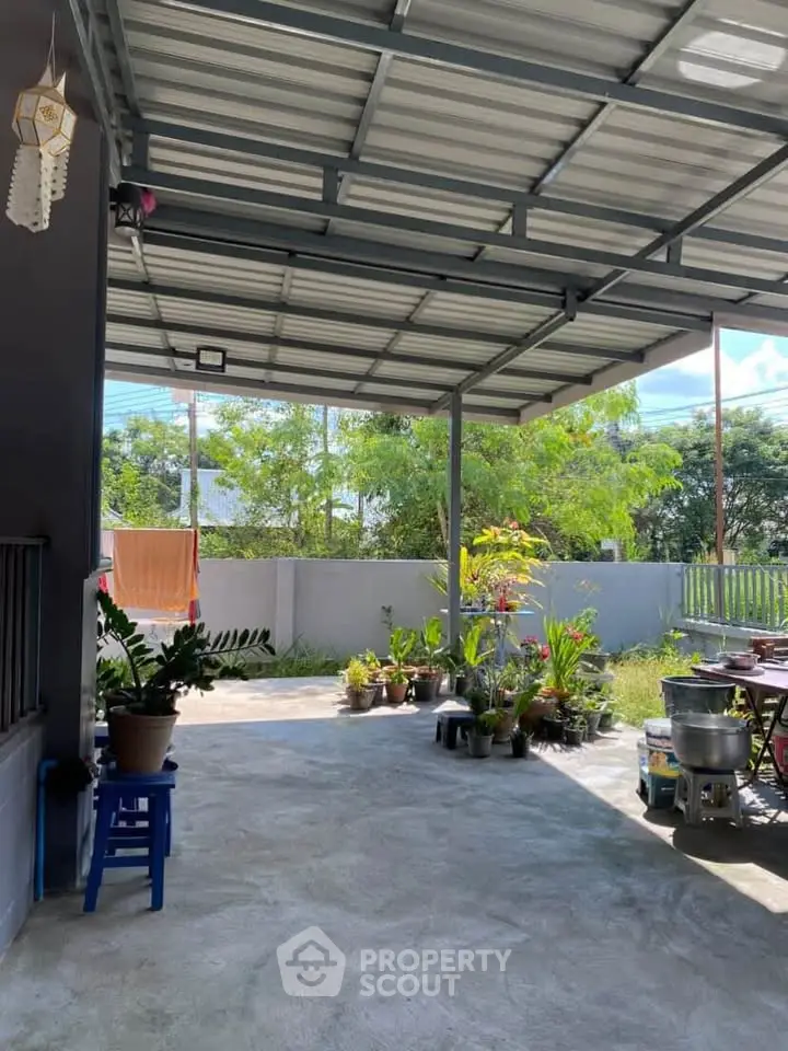 Spacious outdoor patio with metal roof and lush greenery, perfect for relaxation and gatherings.