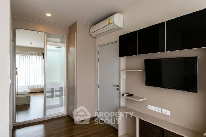 Modern apartment interior with sleek TV setup and air conditioning, showcasing contemporary living space.