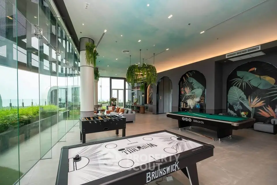 Luxurious game room with pool table and foosball, featuring modern decor and stunning garden views.