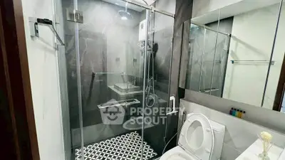 Modern bathroom with glass shower enclosure and stylish black and white tiles.