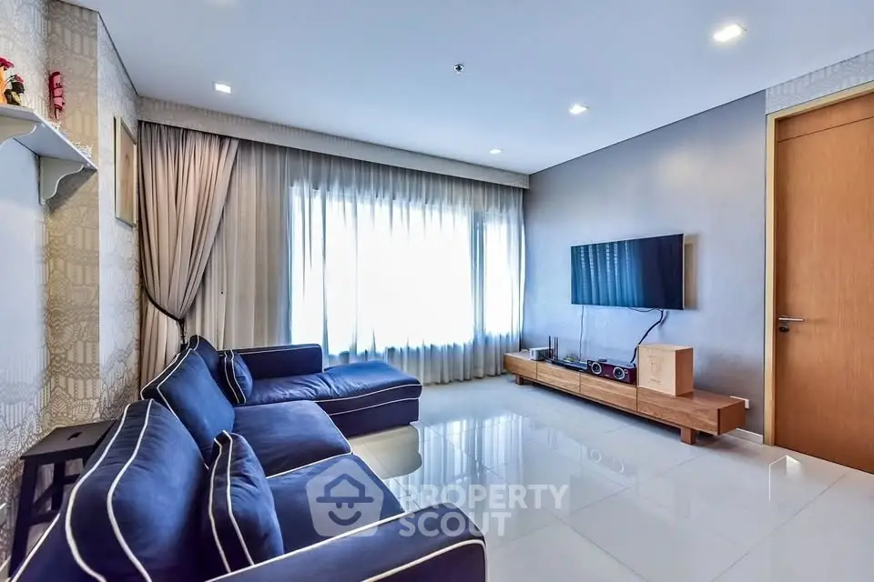 Modern living room with sleek blue sofas and wall-mounted TV