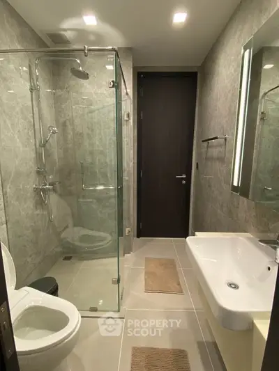 Modern bathroom with glass shower and sleek fixtures in luxury apartment.