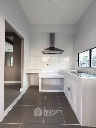 Modern kitchen with sleek design and stainless steel range hood, featuring open layout and ample natural light.